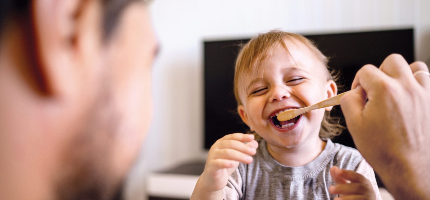 Isä auttaa pientä poikaa pesemään hampaansa. Isä huolehtii lapsesta.