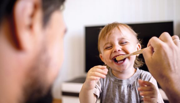Isä auttaa pientä poikaa pesemään hampaansa. Isä huolehtii lapsesta.