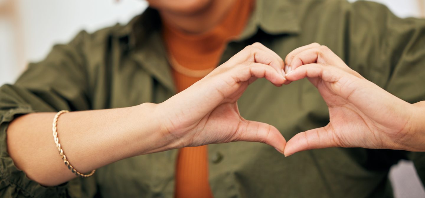 Woman, heart and hands closeup for care, kindness and emoji for charity, peace and wellness. Happy female person with finger shape for heart.