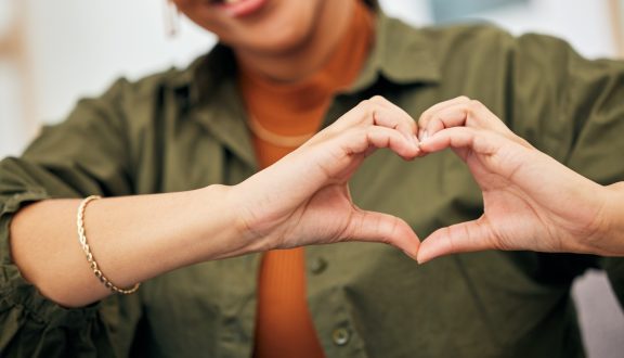 Woman, heart and hands closeup for care, kindness and emoji for charity, peace and wellness. Happy female person with finger shape for heart.